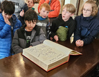 Die Schüler sichtlich fasziniert von der Zeichnung des Künstlers James Rizzi im goldenen Buch des Rathauses 
˜ Bildnachweis: Dr. Lorena Pethig